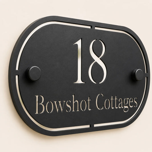 Close-up angled view of personalised black oval acrylic house sign with mirror silver number and lettering
