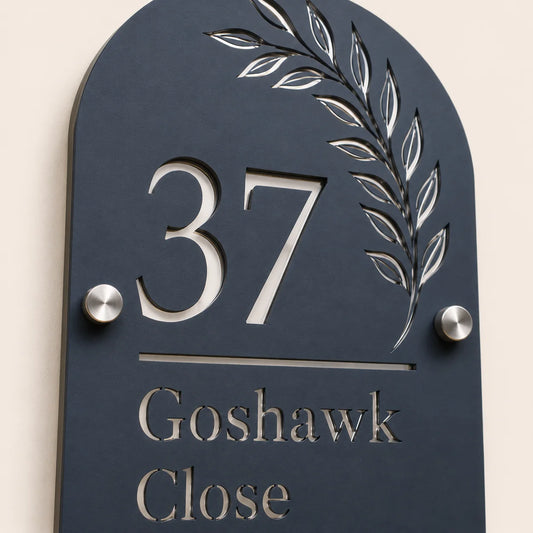 Close-up angled view of personalised denim blue arch acrylic house sign with leaf design and lettering