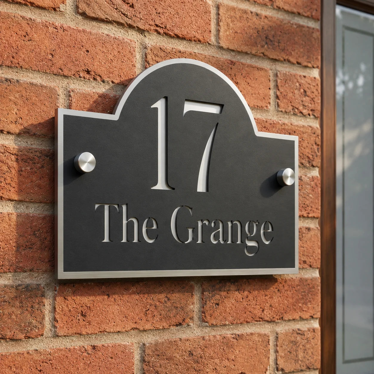 Close-up of personalised black and mirror silver acrylic arch house sign mounted on an exterior brick wall