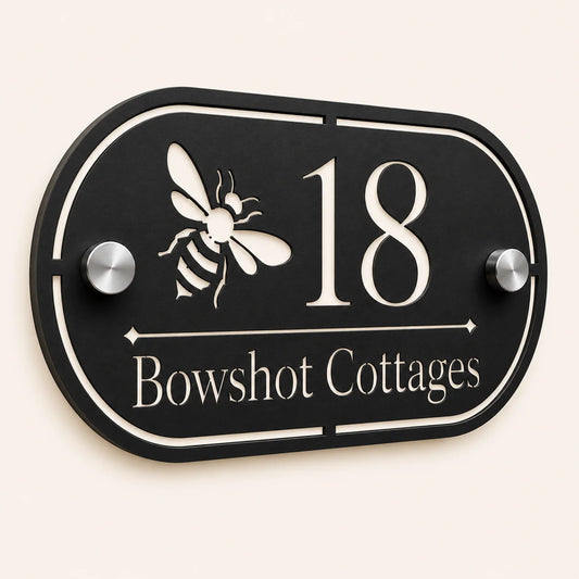 Close-up angled view of personalised black oval acrylic house sign with mirror silver bee design and lettering