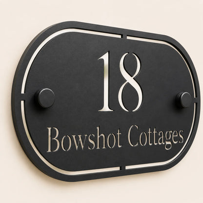 Close-up angled view of personalised black oval acrylic house sign with mirror silver number and lettering
