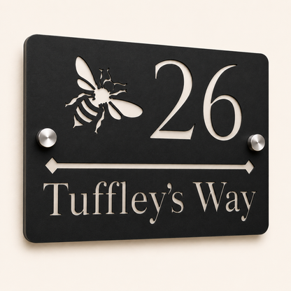 Close-up angled view of personalised black rectangular acrylic house sign with mirror silver bee design and lettering