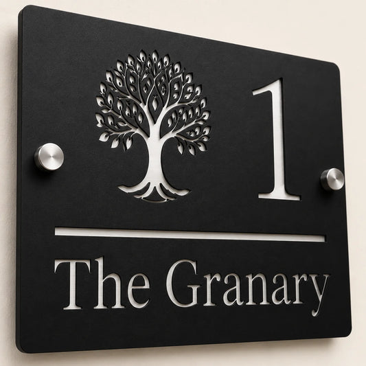Close-up angled view of personalised black rectangular acrylic house sign with mirror silver tree design and lettering