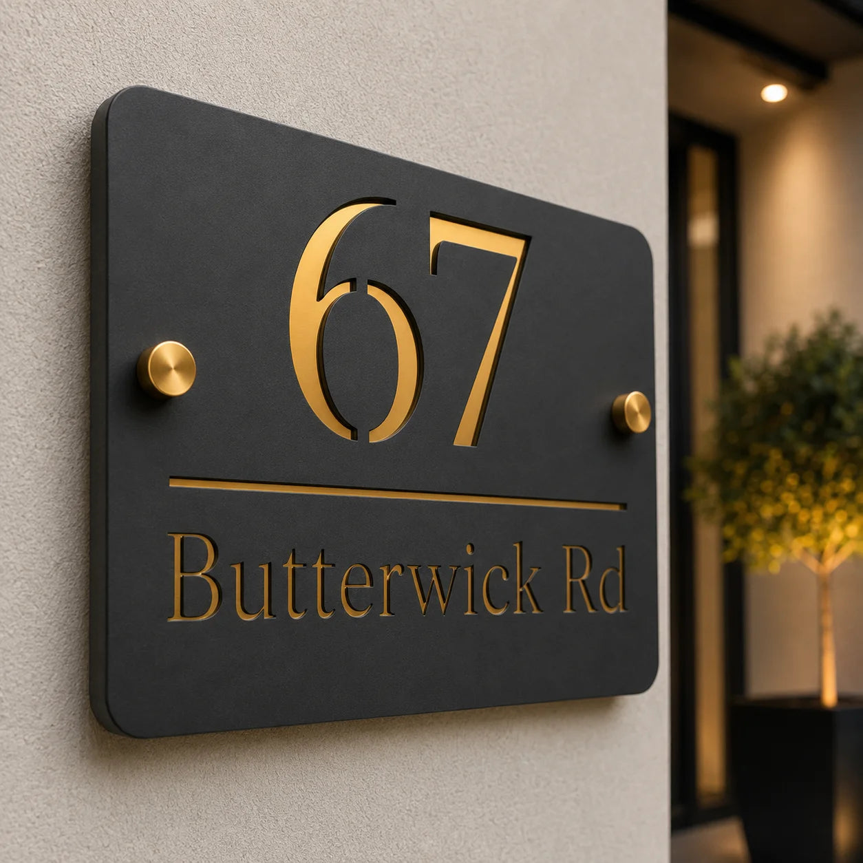 Detailed close-up of a modern mineral grey acrylic house sign featuring raised gold mirror number 67, engraved address and premium brass stand-off fixings installed on an exterior wall.