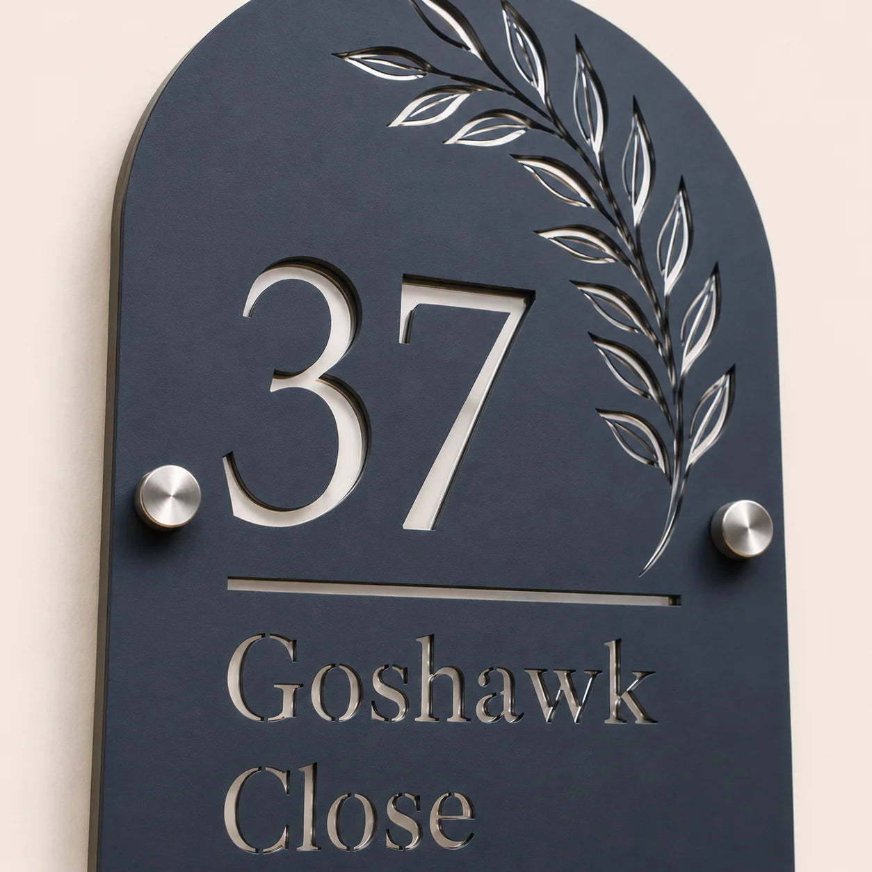 Close-up angled view of personalised denim blue arch acrylic house sign with leaf design and lettering