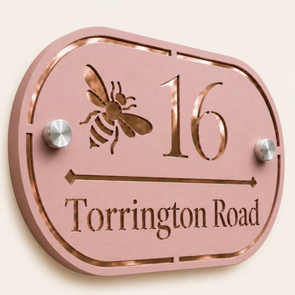 Close-Up
Close-up angled view of personalised dusky pink oval acrylic house sign with mirror rose gold bee design and lettering