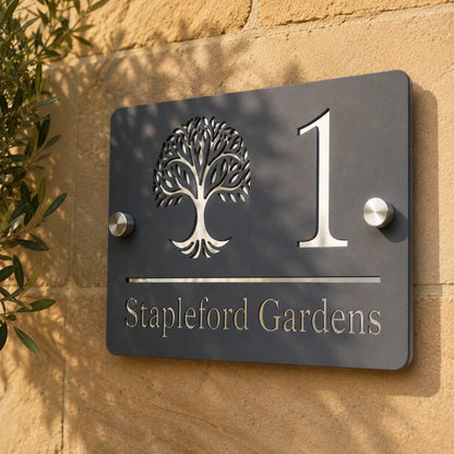 Close-up of personalised mineral grey rectangular acrylic house sign with mirror silver detailing mounted on a stone wall