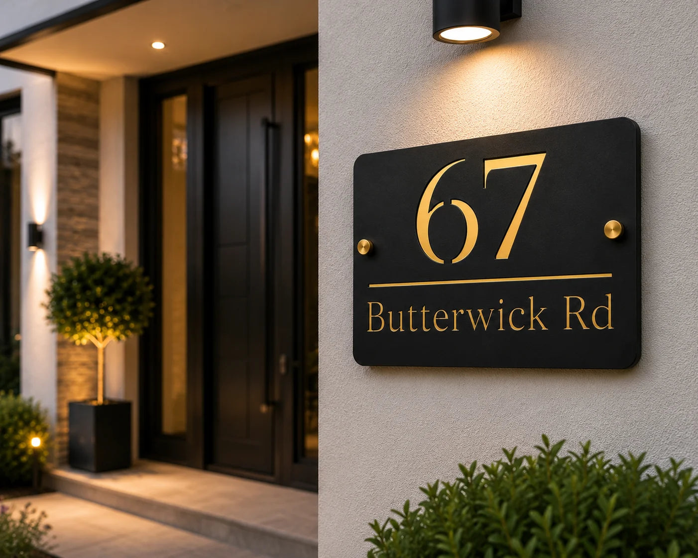 Personalised black & gold rectangular acrylic house sign with mirror gold detailing mounted beside a modern front door