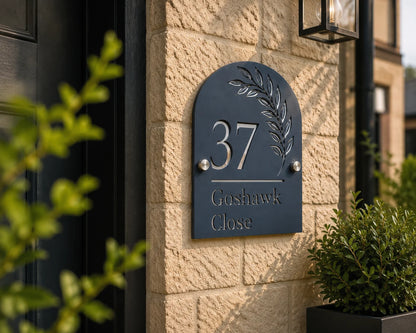 Personalised denim blue arch acrylic house sign with leaf design mounted beside a front door