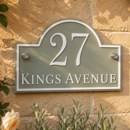 Close up of personalised sage green arch acrylic house sign with raised white lettering mounted on an exterior stone wall