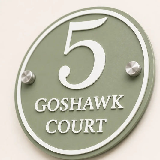Close-up of personalised sage green round acrylic house sign showing raised white lettering and stainless steel fixings