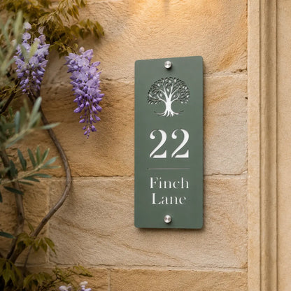 Close-up of sage green personalised house sign with tree design mounted on a stone wall