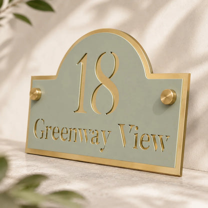 Sage Green and Mirror Gold Arch Acrylic House Sign Close Up blurred leafs in the background 