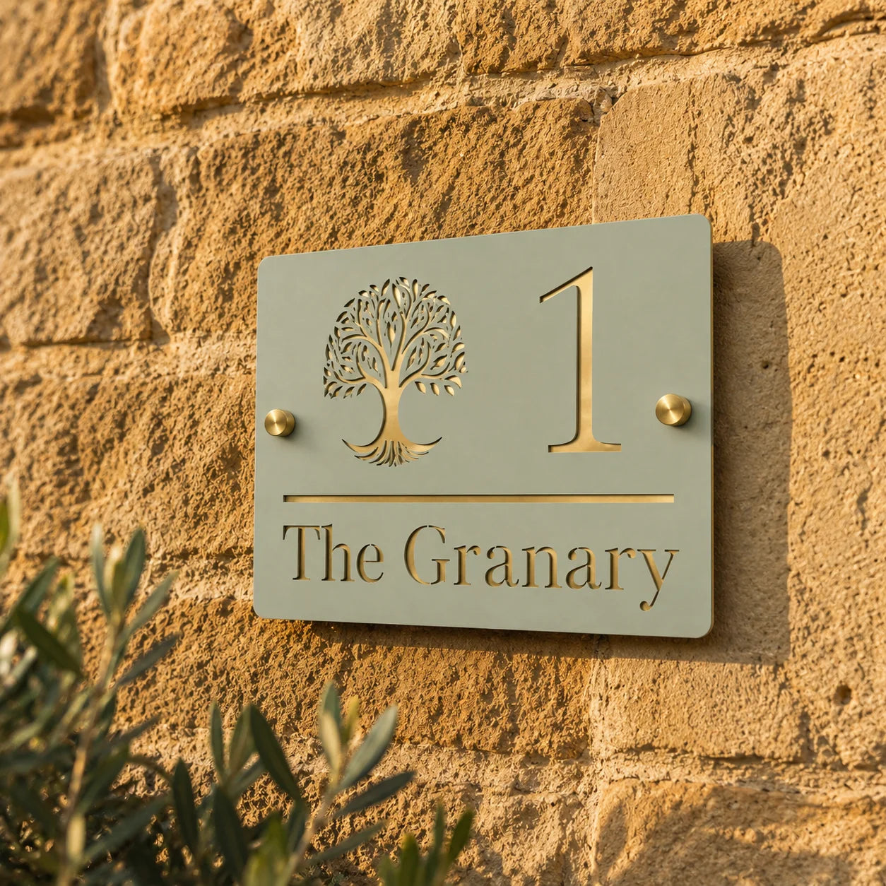 Close-up of personalised sage green and mirror gold acrylic house sign mounted on a stone wall showing the tree design and gold details