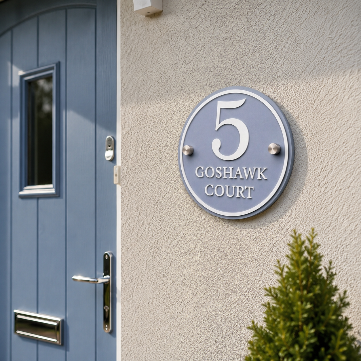 Close-up of dusky blue acrylic house sign with matt white lettering installed beside a front door