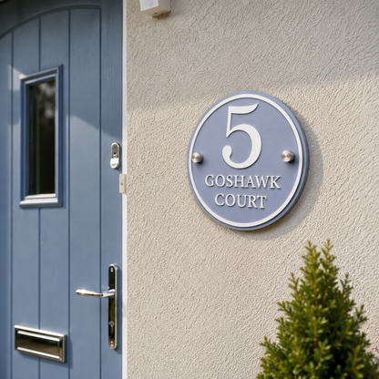 Close-up of dusky blue acrylic house sign with matt white lettering installed beside a front door