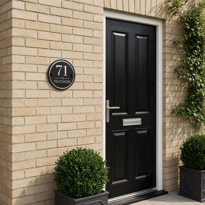 Personalised black and mirror silver round house sign mounted beside a modern front door